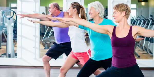 Vier Kursteilnehmer strecken im Ausfallschritt einen Arm nach vorne